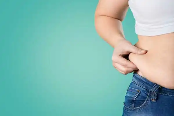 Image of woman pinching her love handles to show weight gain Esher